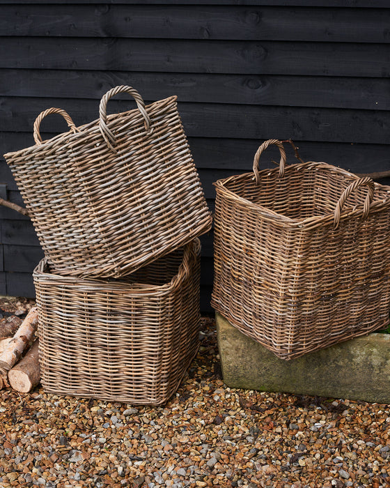 handmade  weaved rattan log basket in front of wood pile. 